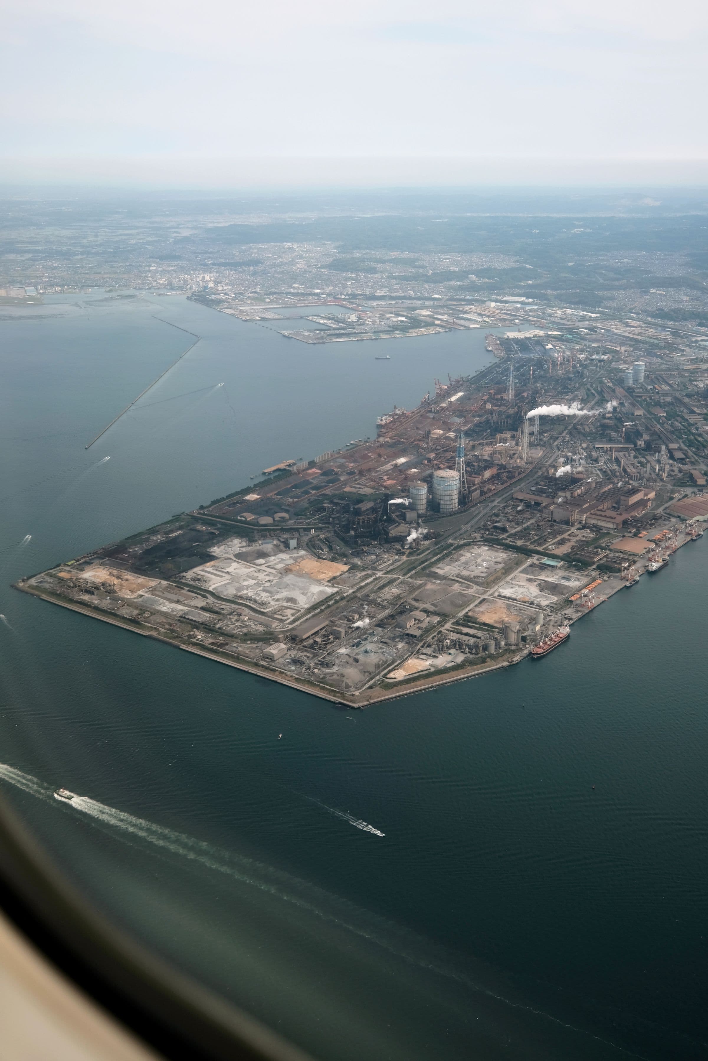Aerial view of an industrial platform in Tokyo Bay, showing plants, serviced land and quays surrounded by water