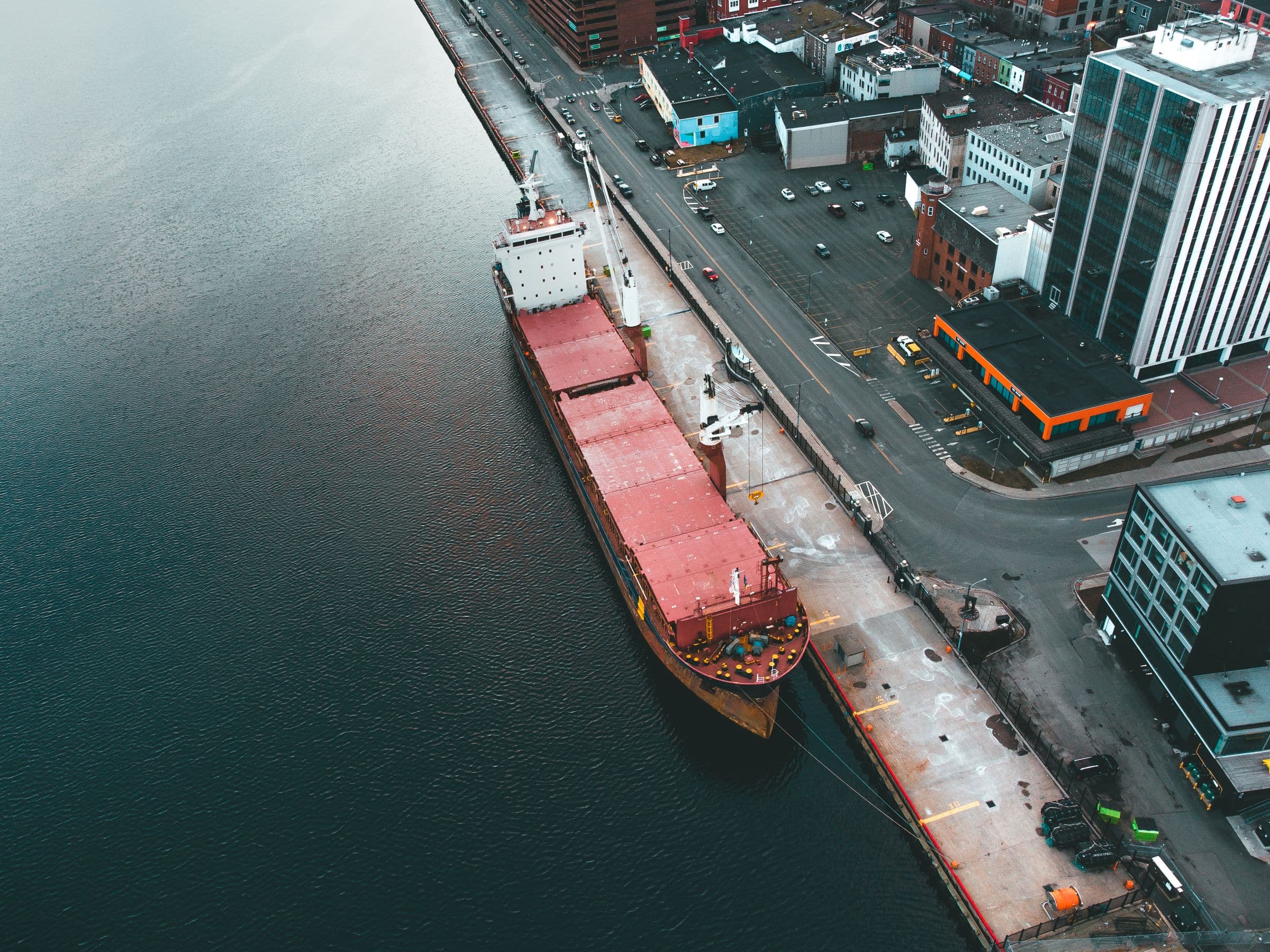 Cargo vessel berthed against an urban industrial waterfront, seen from above